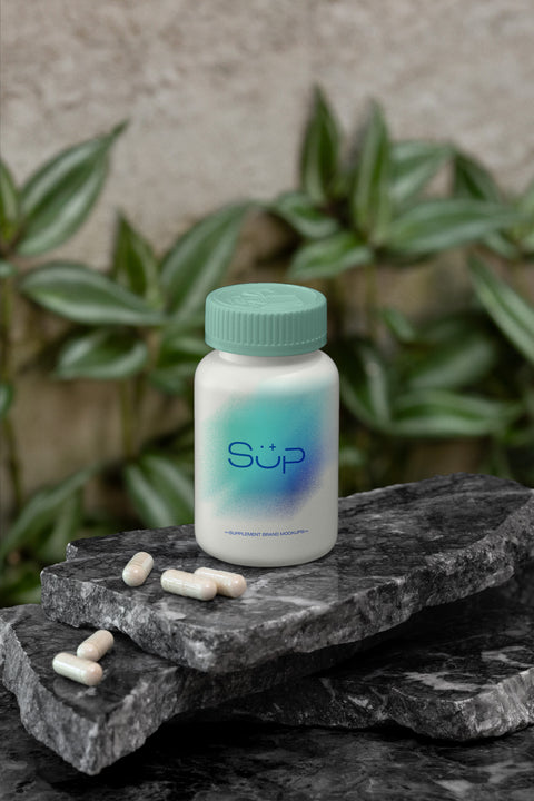 Pill Bottle Packaging Mockup sitting on Black Granite with plants in background